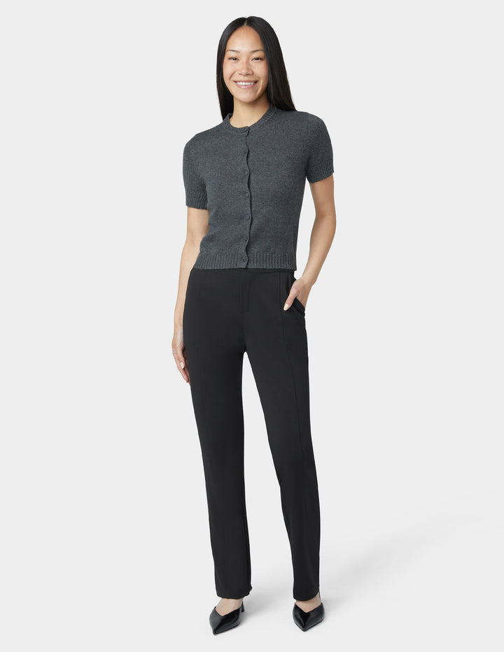 Woman wearing a gray short-sleeve cardigan and black pants on a white background