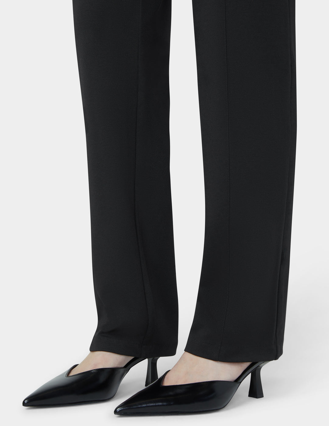 Black high-heeled shoes worn with black pants on a white background