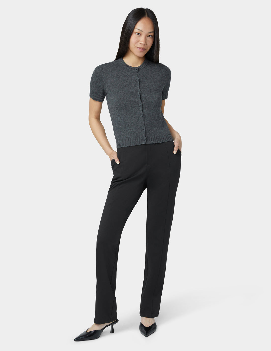 Woman wearing a gray short-sleeve cardigan and black pants on a white background