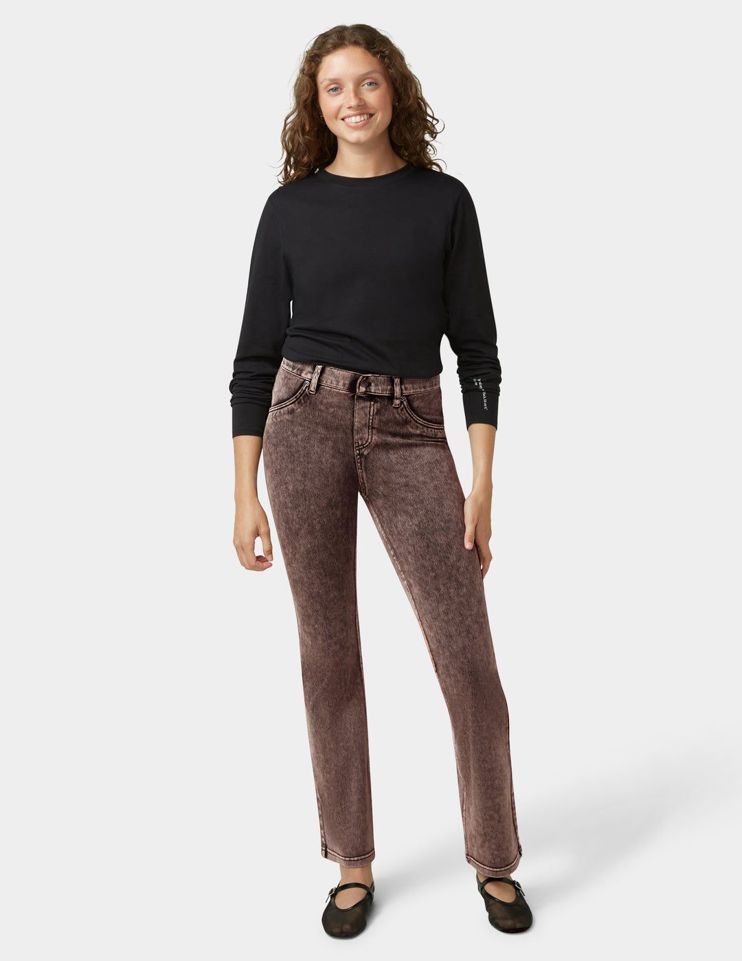 Woman wearing a black top and brown jeans on a white background