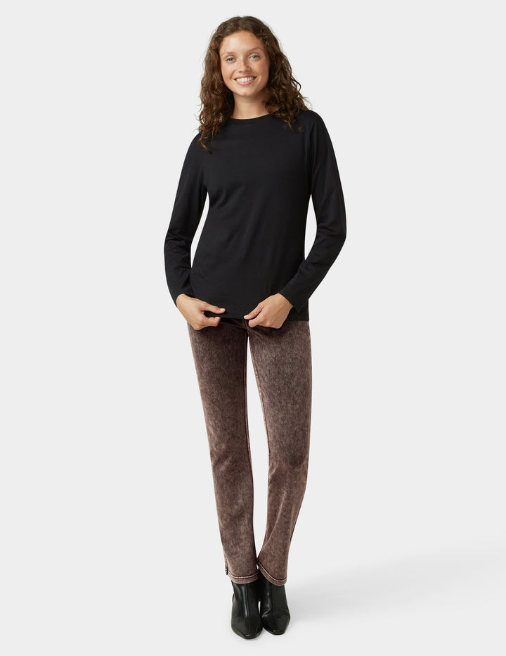 Woman wearing a black long-sleeve top and brown pants on a white background