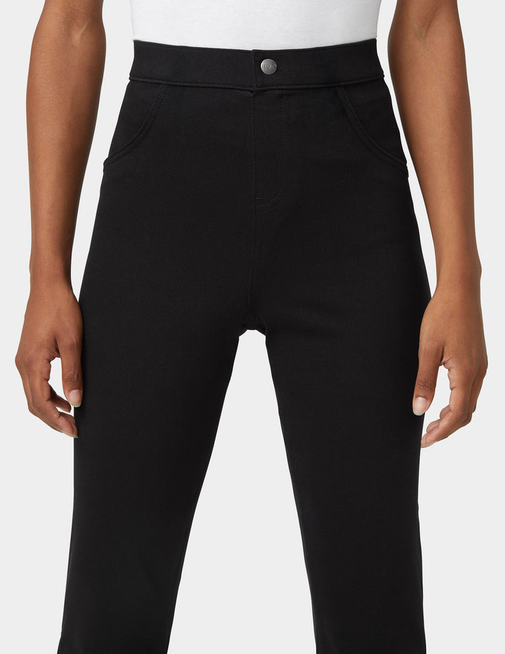 Close up detailed view of a model wearing bootcut black denim bottoms shown at the waist