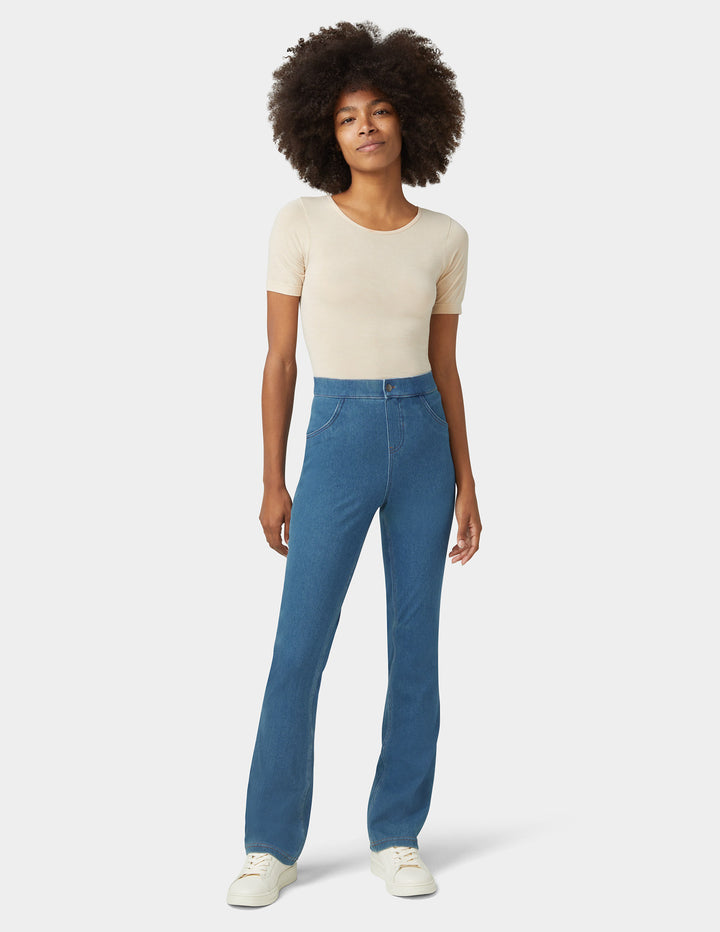 A model wearing bootcut medium wash bottoms and beige top