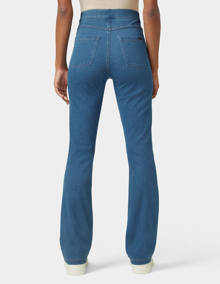 A model wearing bootcut medium wash bottoms backside view