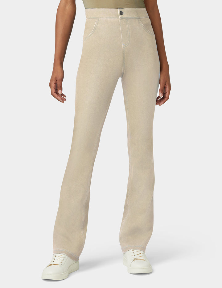 A model wearing a pair of light beige straight-leg jeans with white sneakers, shown from the waist down against a light gray studio background.