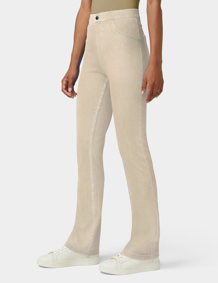 A model wearing a pair of light beige straight-leg jeans with white sneakers, shown from the waist down against a light gray studio background.