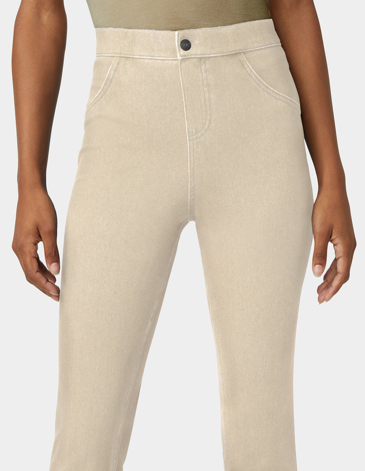 Beige high-waisted slim-fit jeans shown on a model from the waist down, featuring a button closure and front faux pockets.