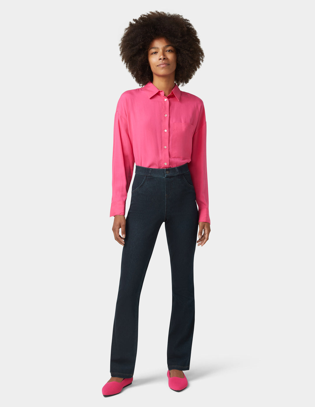 Woman wearing a pink shirt and dark jeans on a white background
