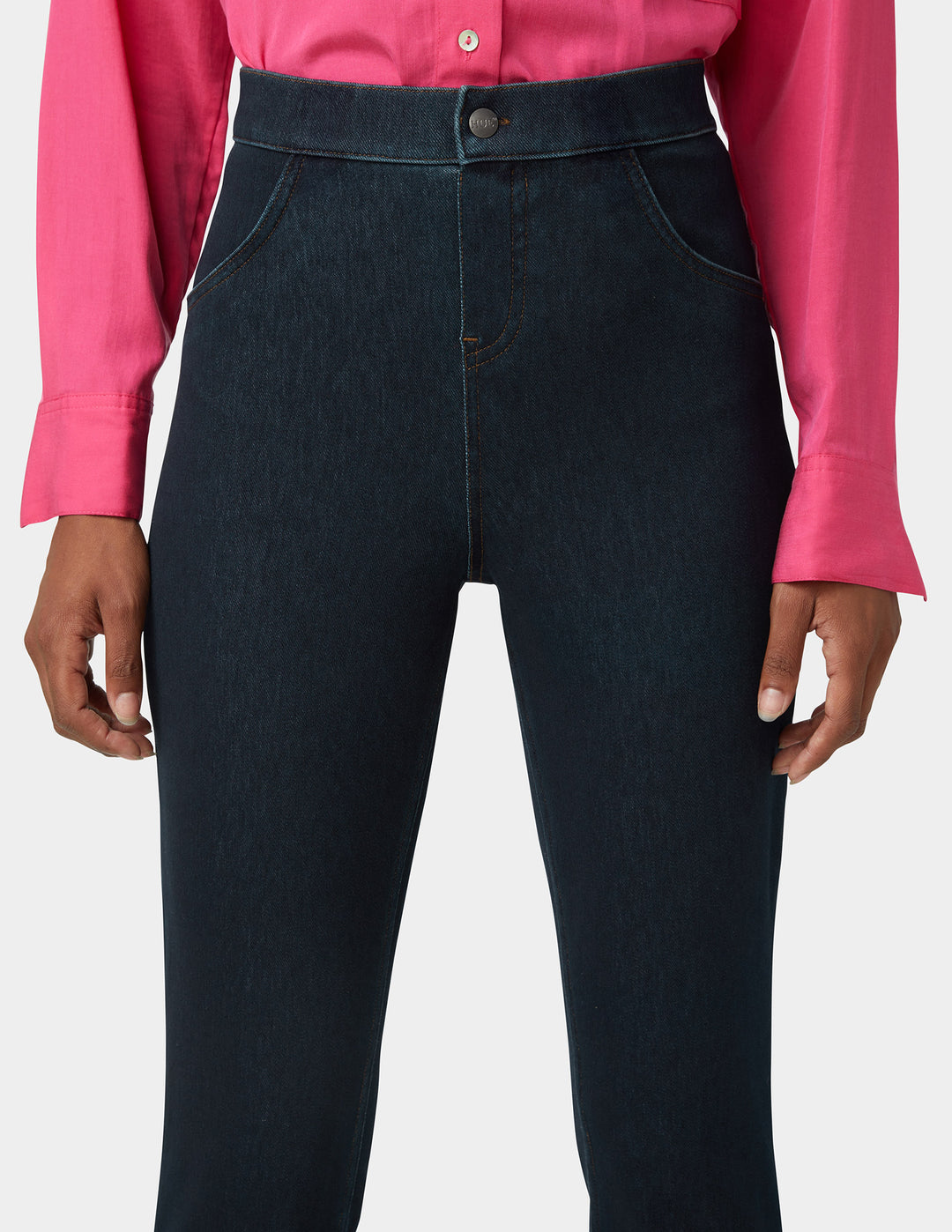 Woman wearing dark blue jeans with a pink shirt on a white background