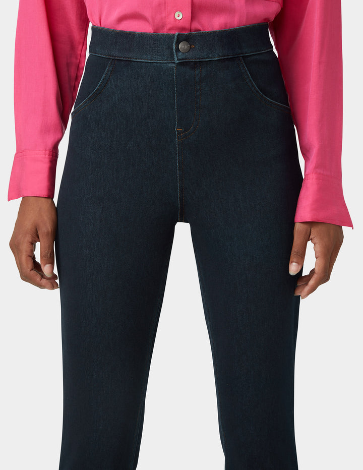 Woman wearing dark blue jeans with a pink shirt on a white background