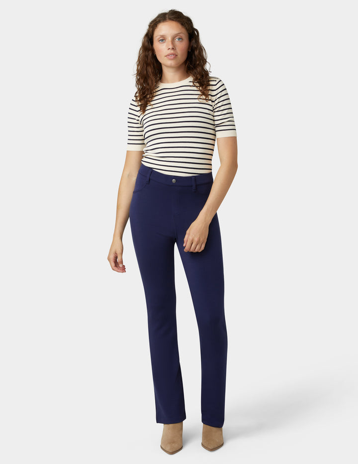 Woman wearing a striped shirt and navy pants on a white background