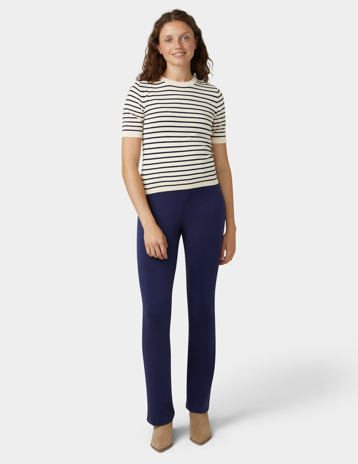 Woman wearing a striped shirt and navy pants on a white background