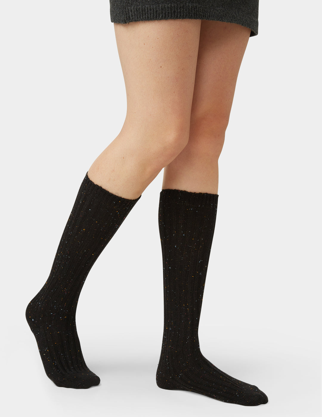 Black knee-high socks worn by a person on a white background