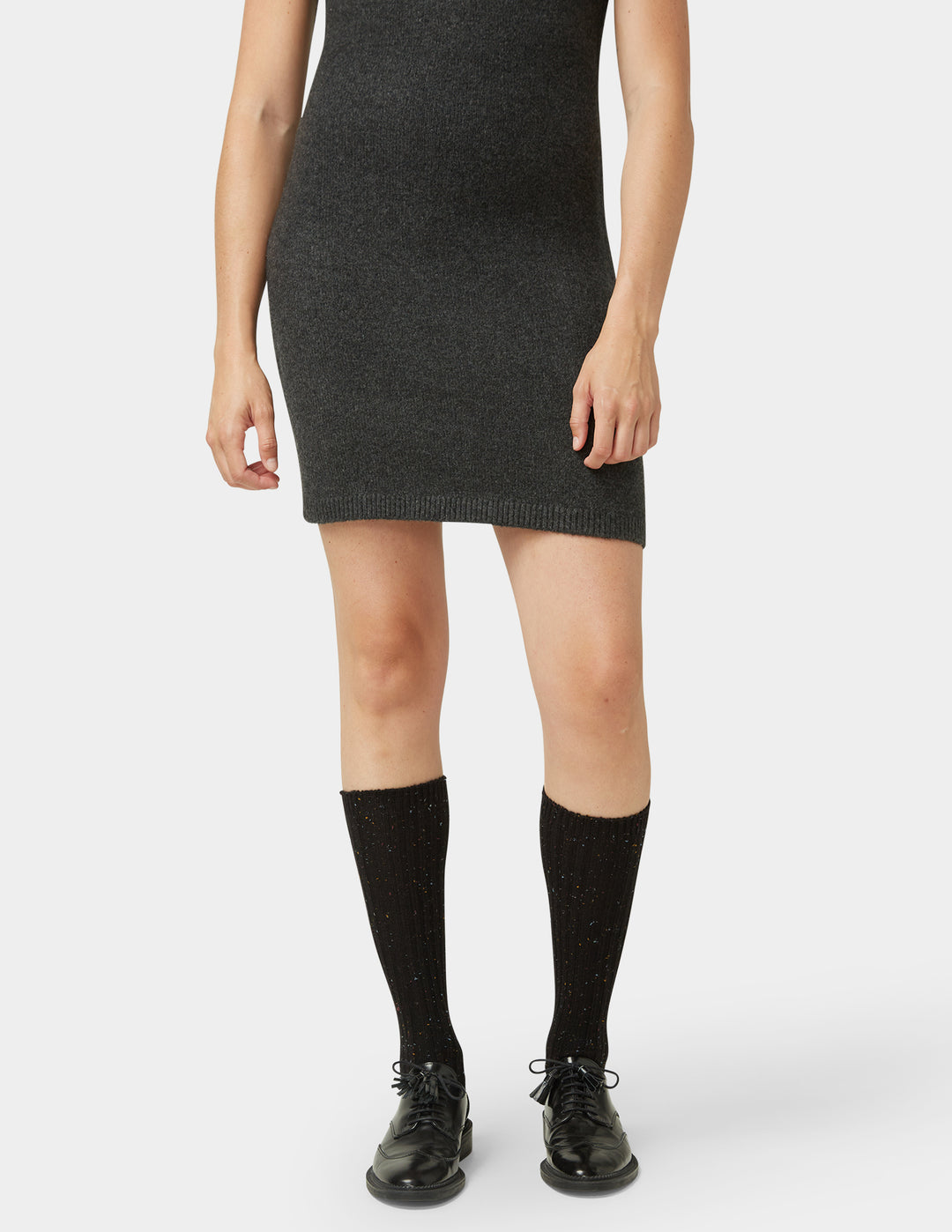 Person wearing a black dress, black knee-high socks, and black shoes on a white background