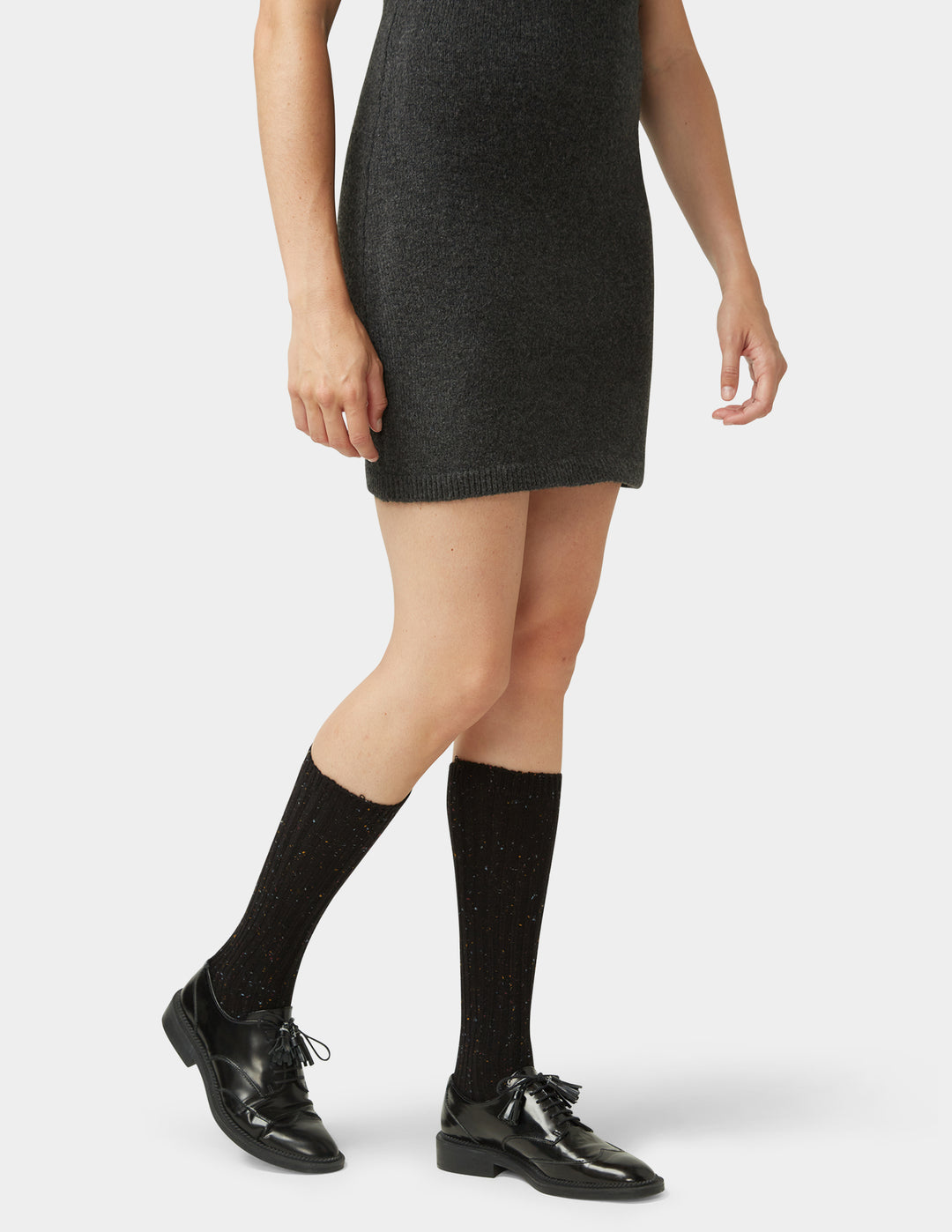 Person wearing a black dress, black knee-high socks, and black shoes on a white background