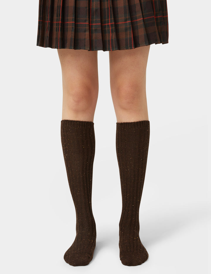 Brown knee-high socks worn with a plaid skirt on a white background