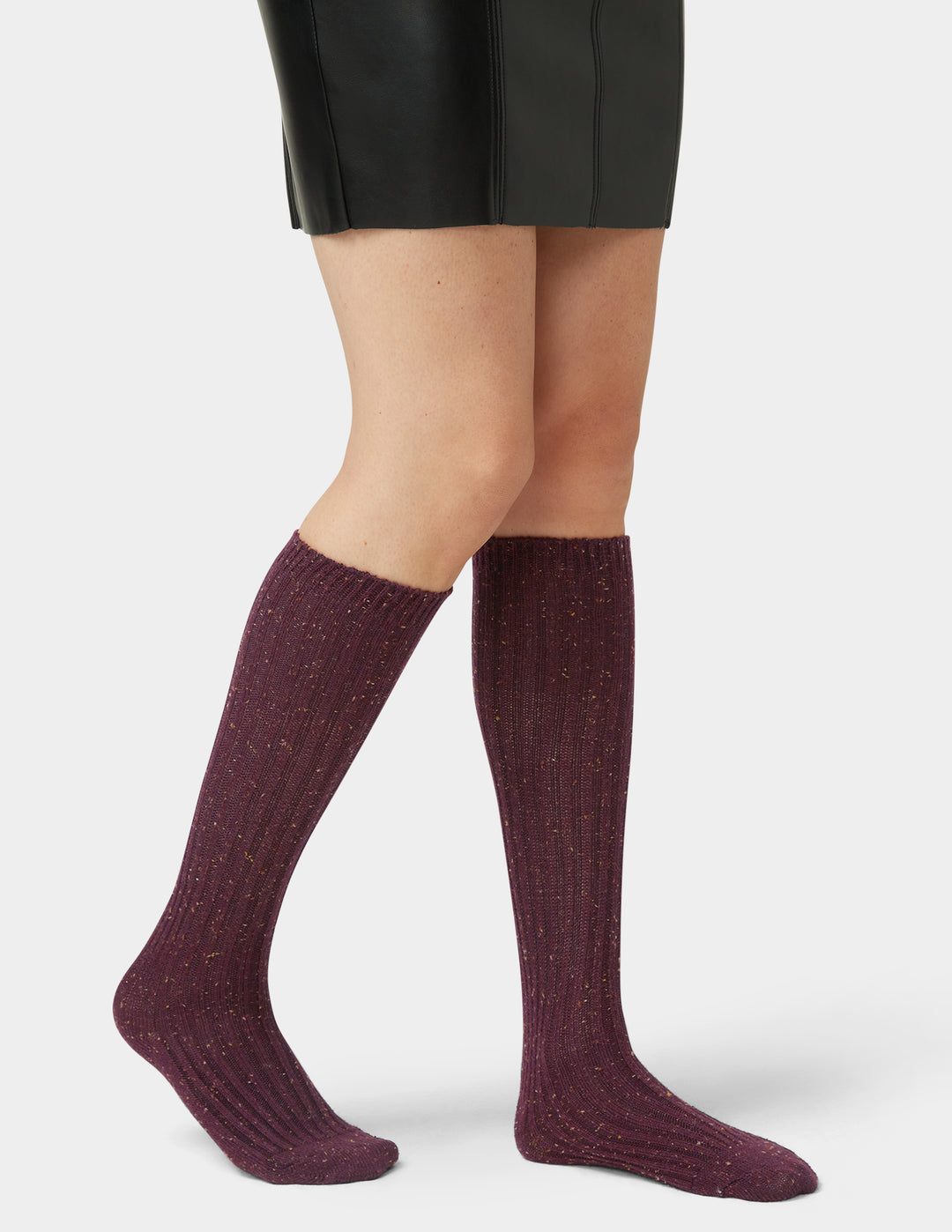 Purple knee-high socks worn with a black skirt on a white background