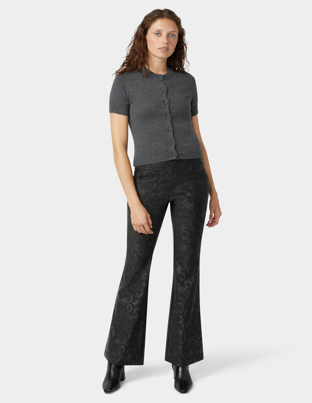 Woman wearing a gray short-sleeve top and black flared pants on a white background