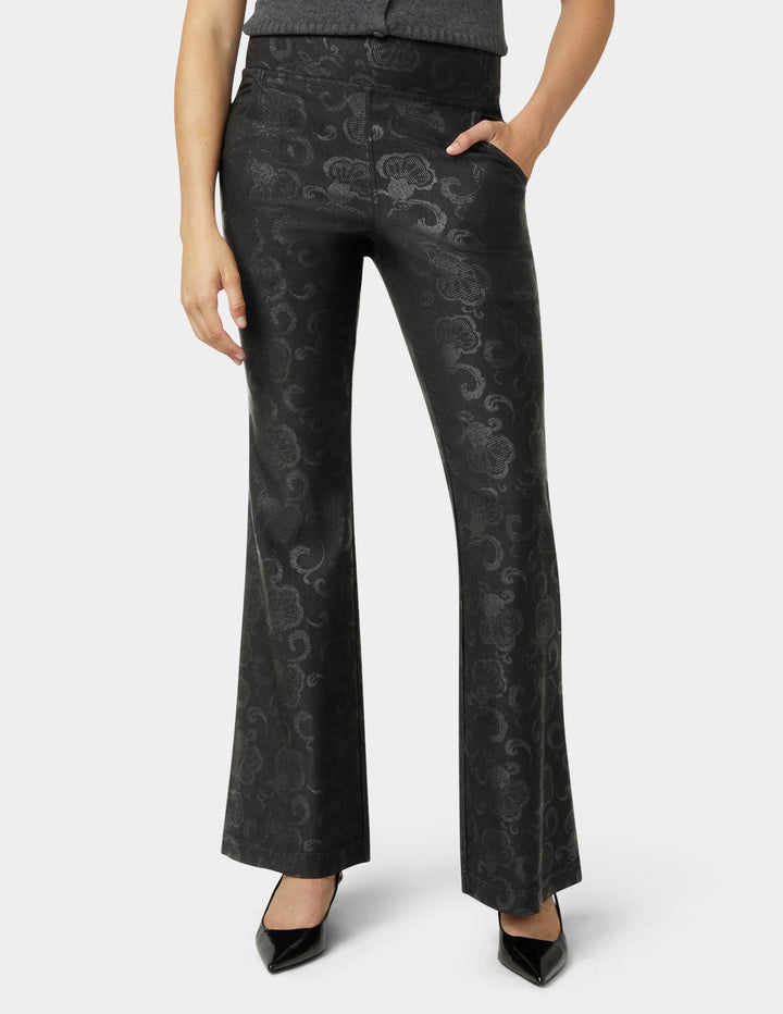 Black patterned pants worn by a person on a white background