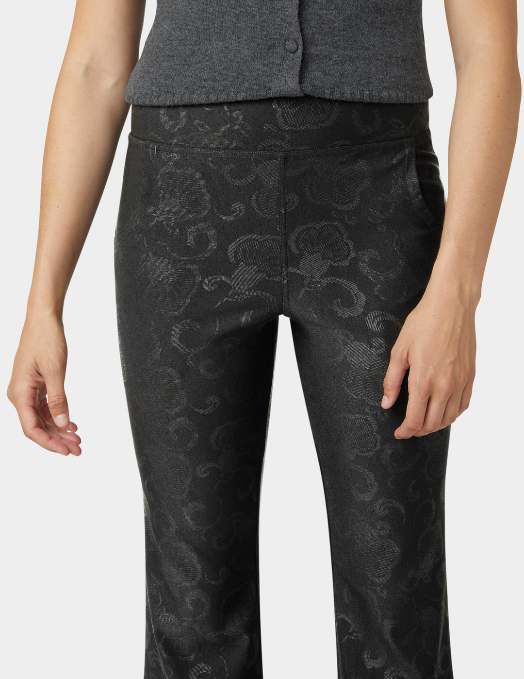 Black patterned pants worn by a person on a white background
