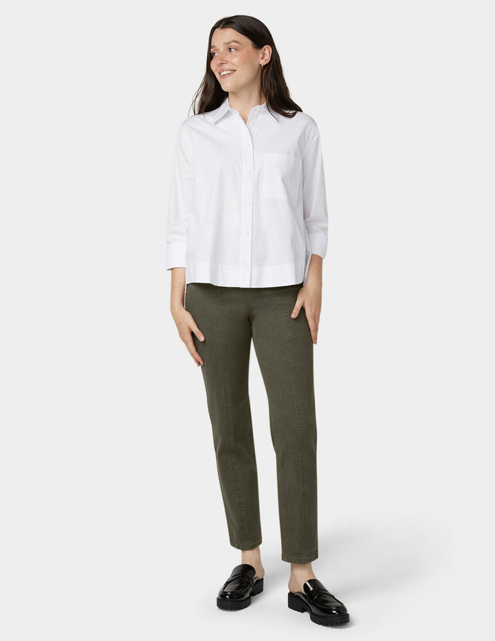 Woman wearing a white shirt and green denim on a white background