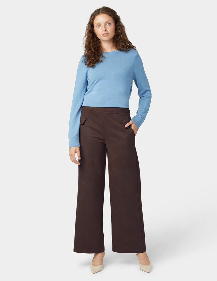 Woman wearing a blue sweater and brown pants on a white background