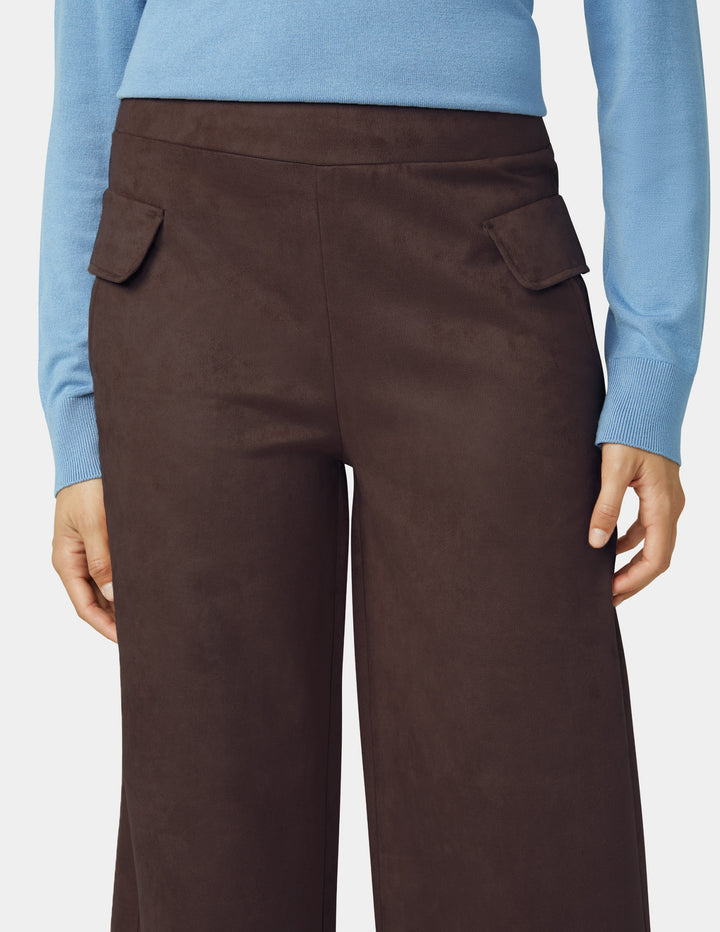Brown pants worn with a light blue sweater on a plain background