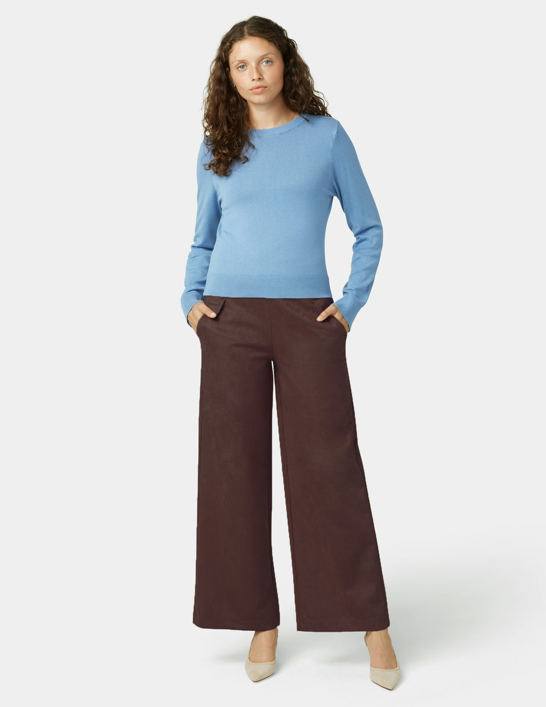 Woman wearing a blue sweater and brown pants on a white background