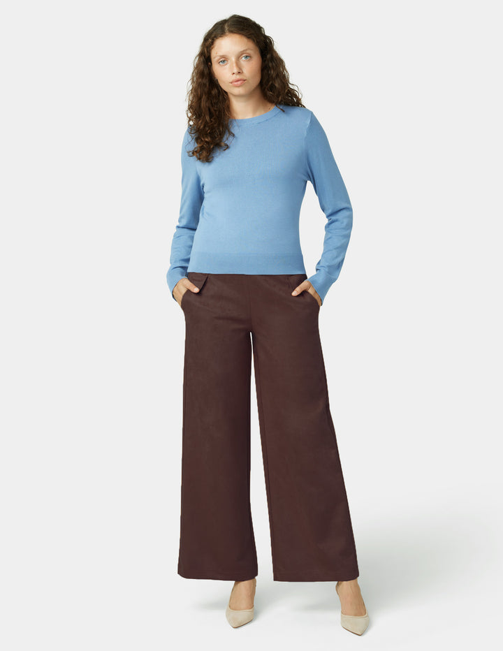 Woman wearing a blue sweater and brown pants on a white background