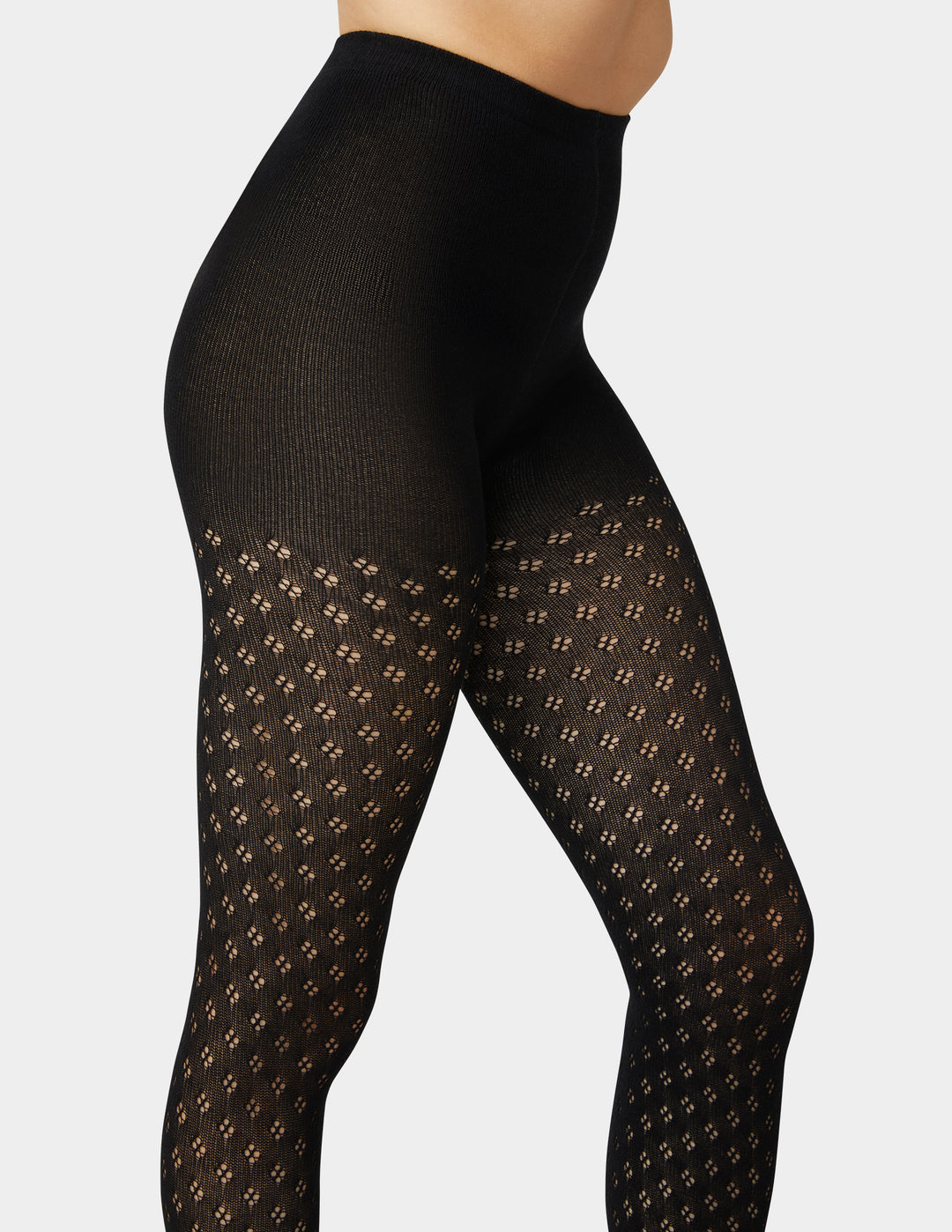 Woman wearing black pointelle sweater tights in black on grey background