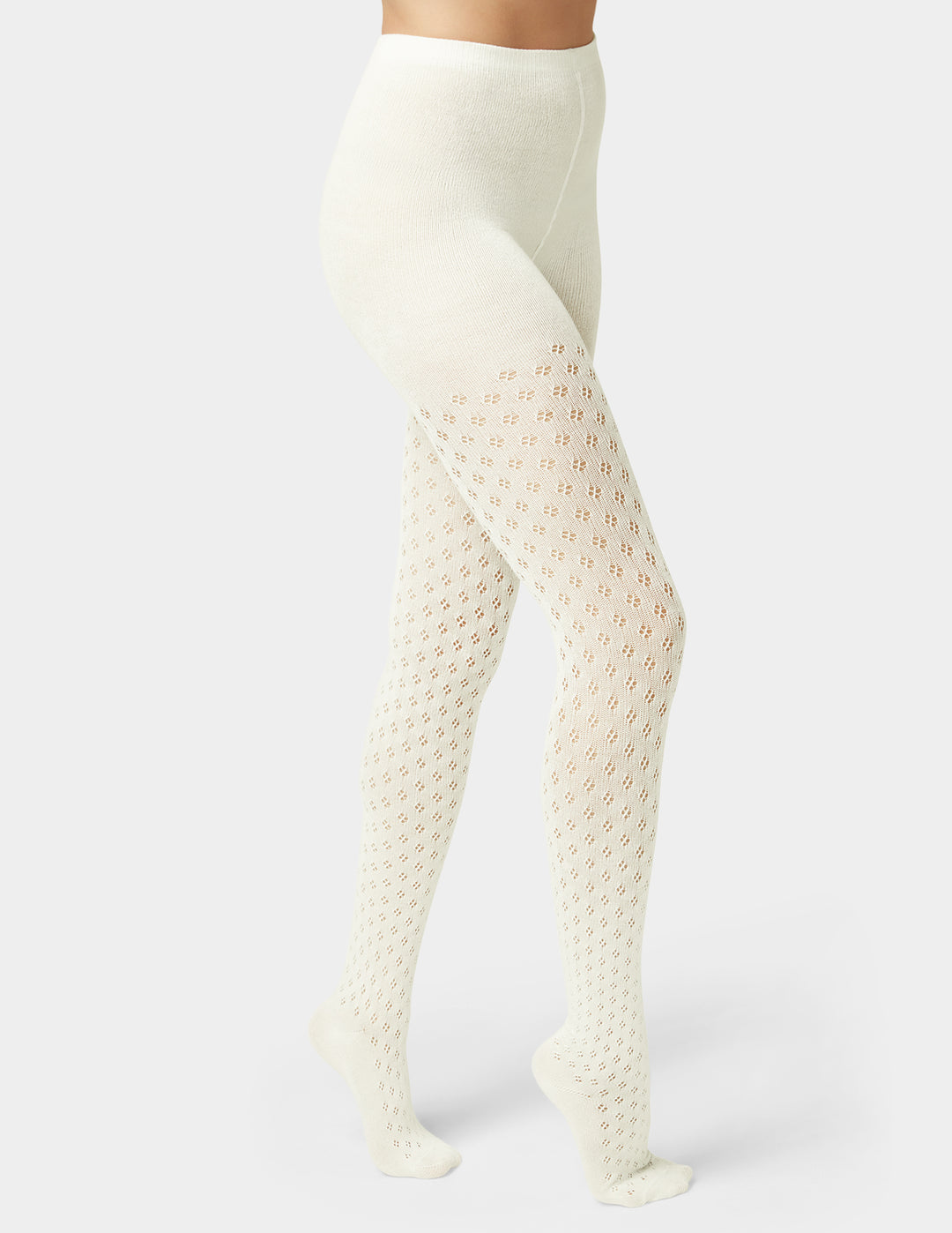 Woman wearing ivory pointelle sweater tights in black on grey background