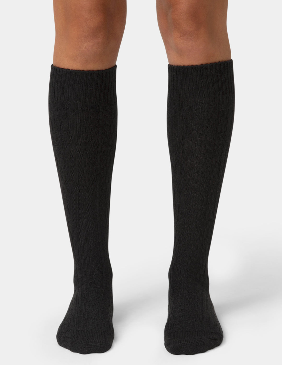 Black knee-high socks worn by a person on a white background