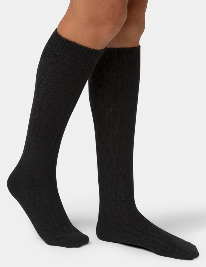 Black knee-high socks worn by a person on a white background