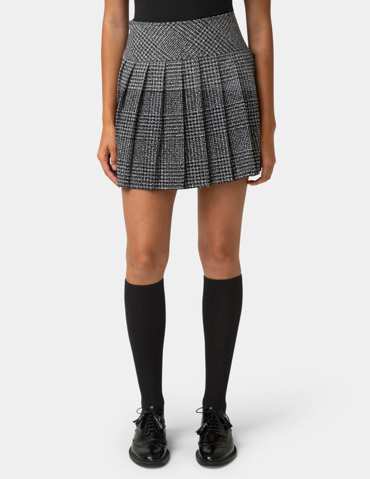 Person wearing a black and white checkered pleated skirt on a white background