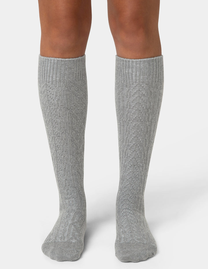 Gray knee-high socks worn by a person on a white background