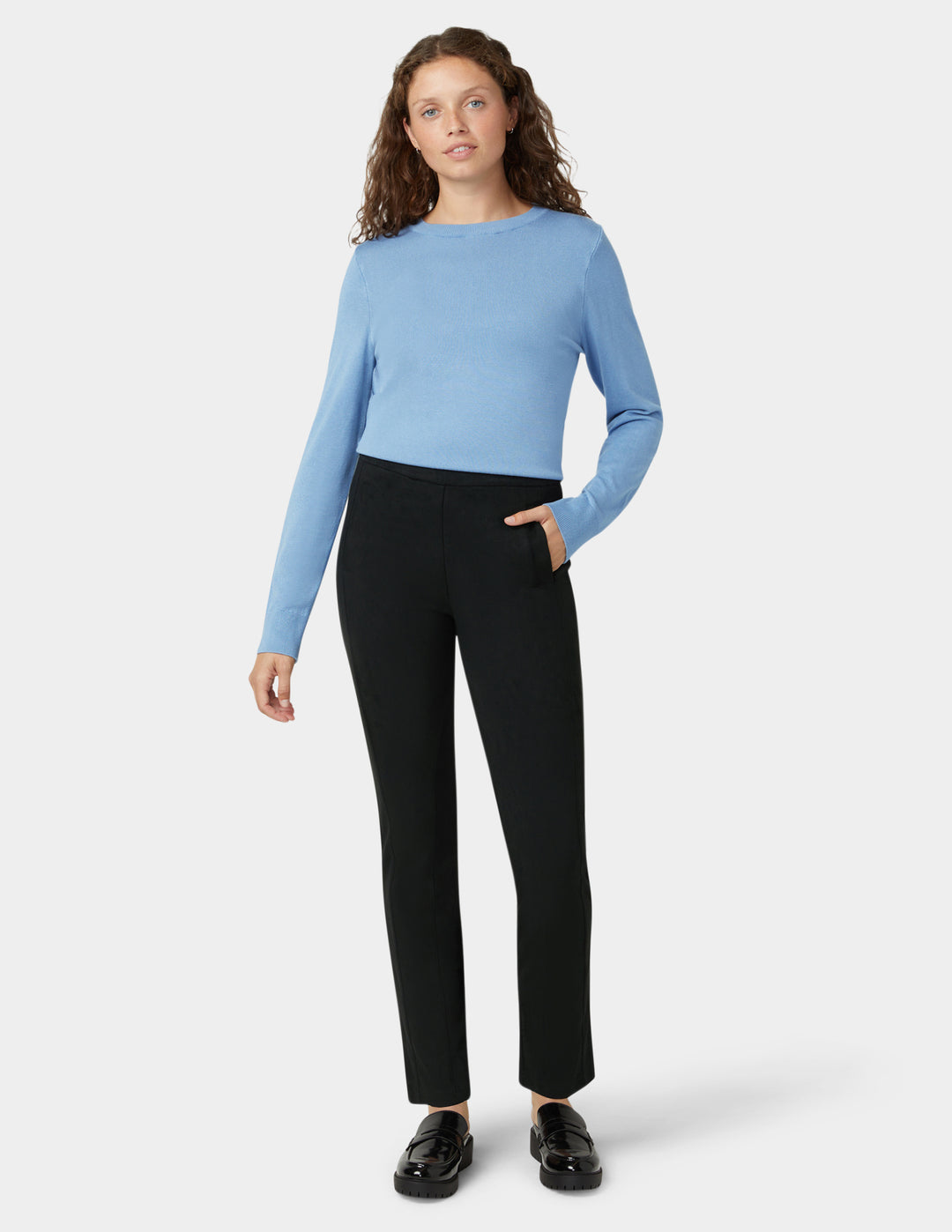 Woman wearing a light blue sweater and black pants on a white background