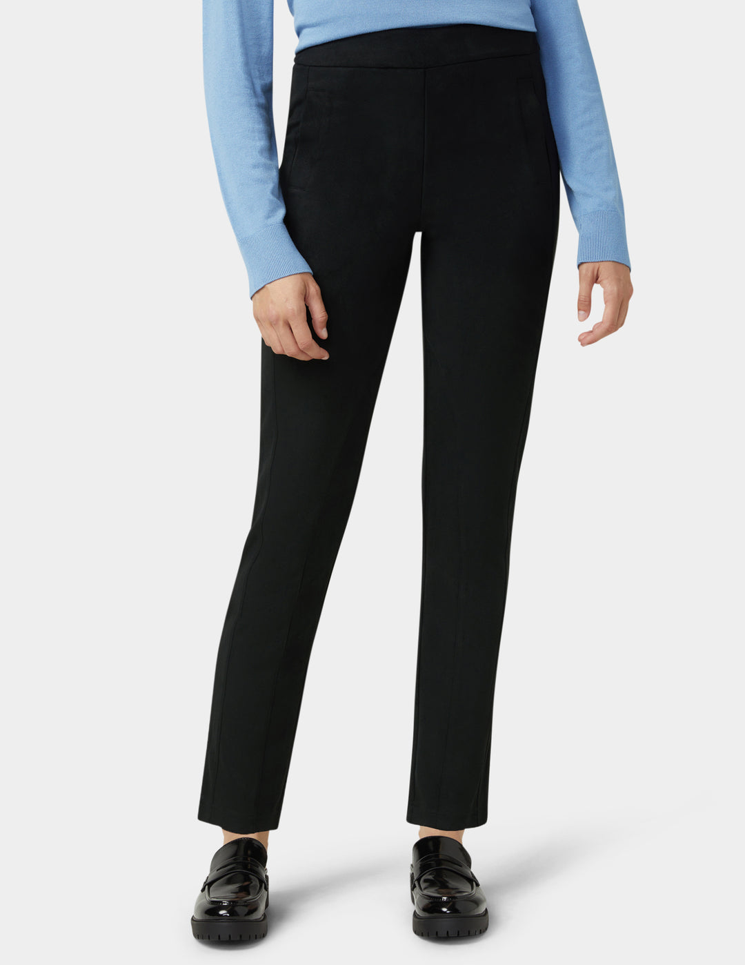 Person wearing black pants with a light blue long-sleeve top on a white background