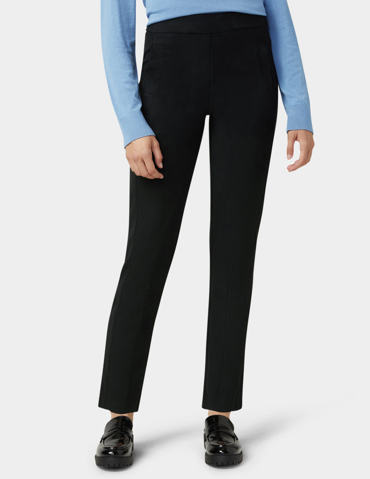 Person wearing black pants with a light blue long-sleeve top on a white background