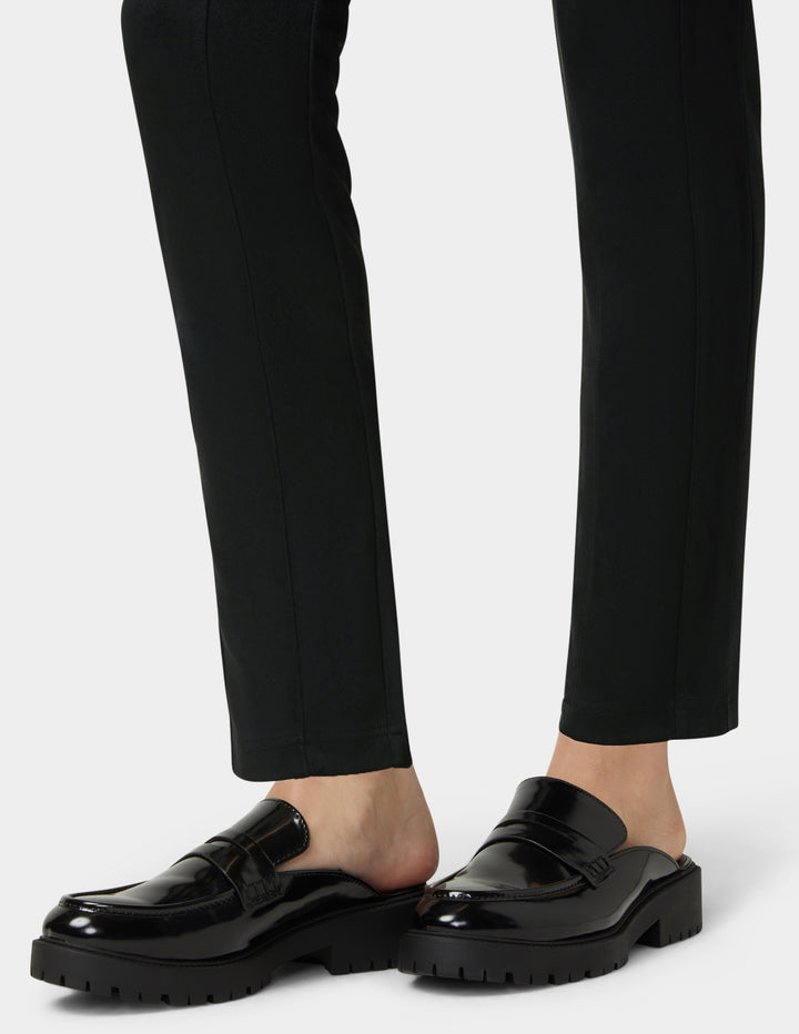 Black loafers worn with black pants on a white background