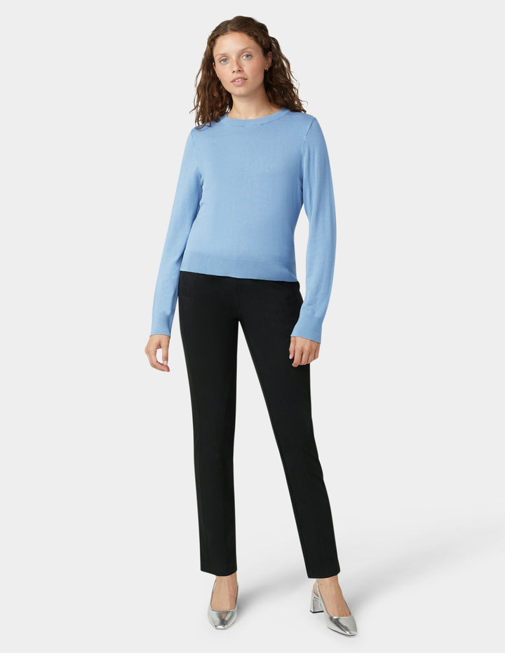 Woman wearing a light blue sweater and black pants on a white background