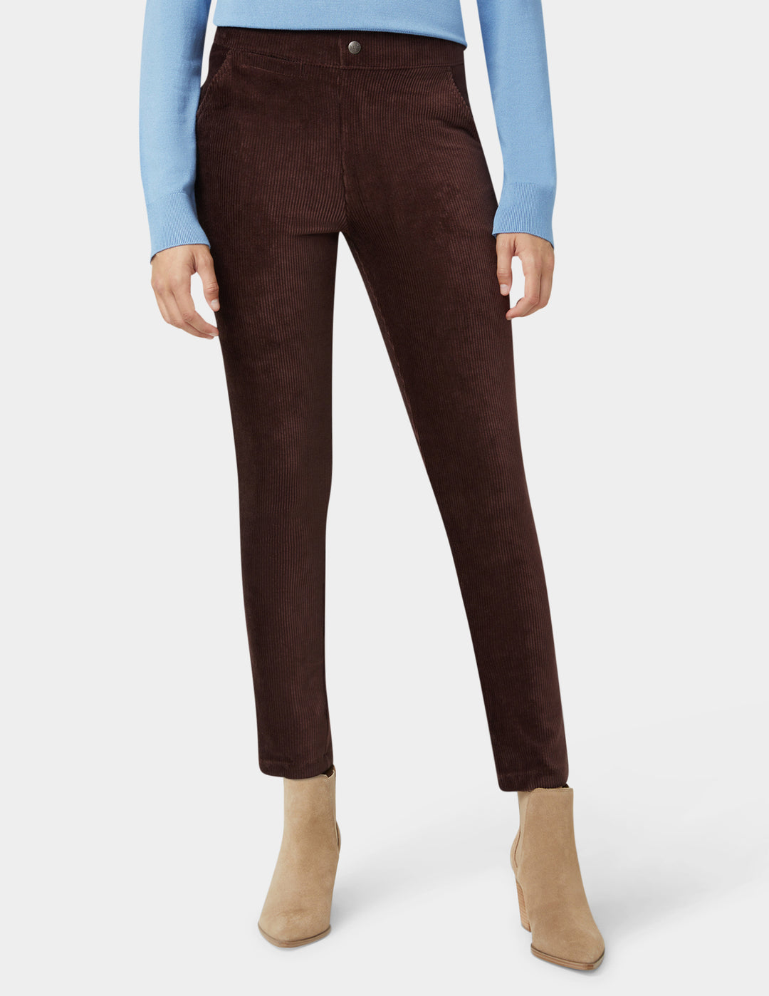 Brown corduroy pants worn with a light blue sweater and beige boots on a white background
