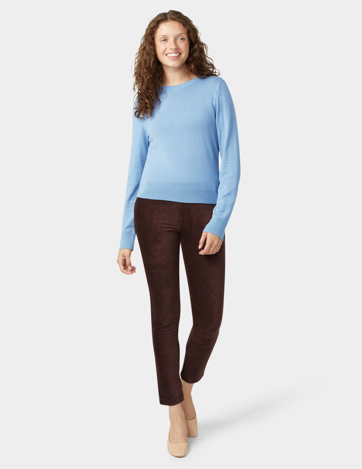 Woman wearing a blue sweater and brown pants on a white background