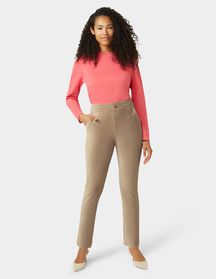 Woman wearing a pink top and beige pants on a white background