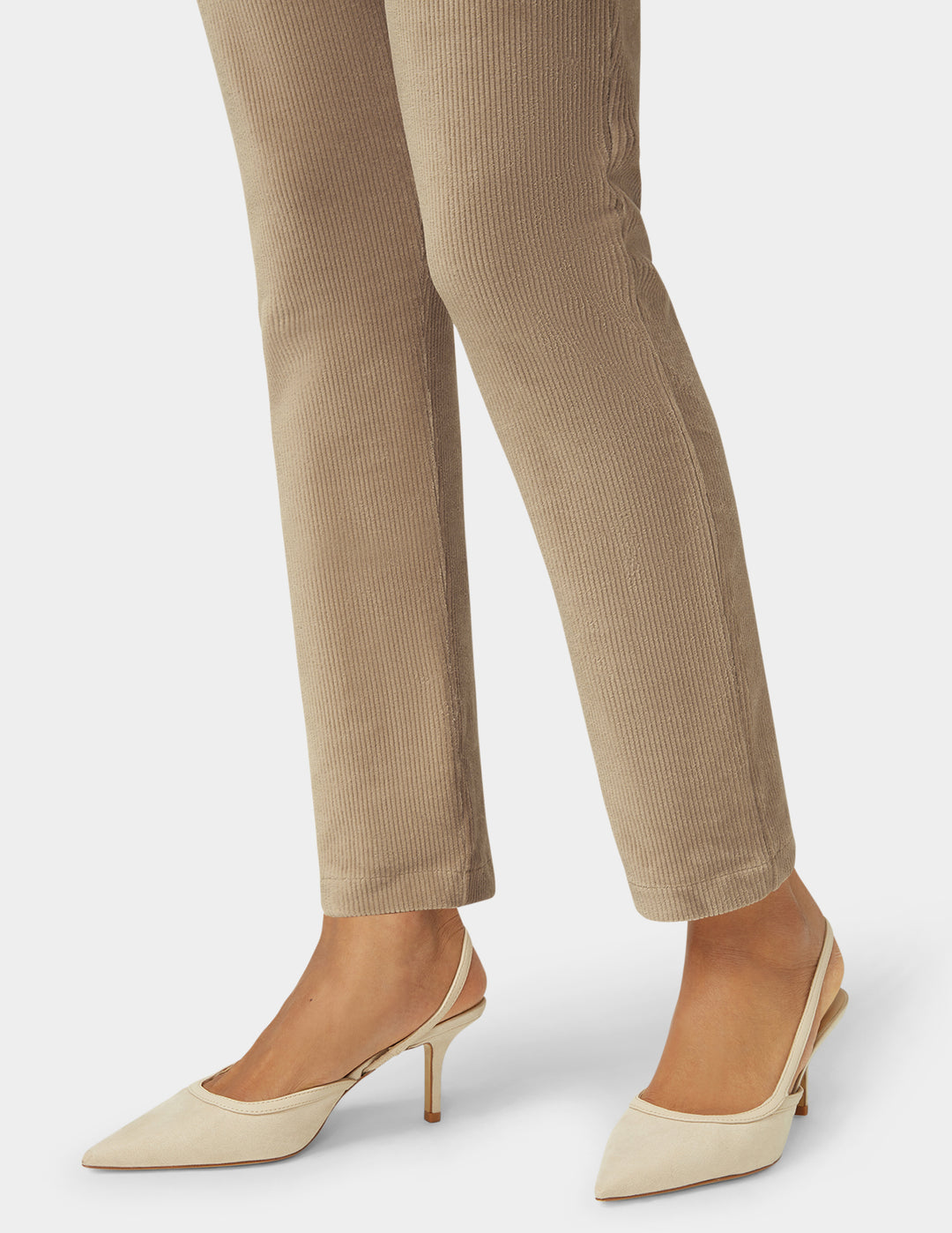 Beige corduroy pants with beige high-heeled shoes on a white background