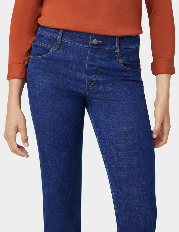 Blue jeans worn by a person with an orange shirt on a white background