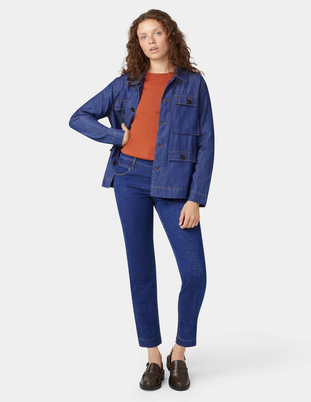 Woman wearing a blue denim jacket and jeans on a white background