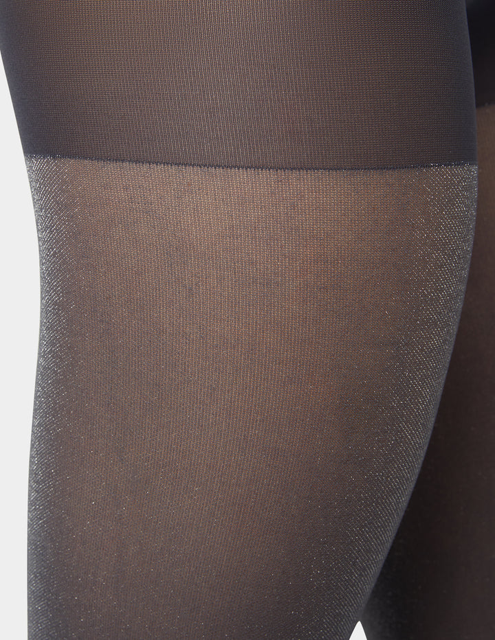 Close-up of silver grey metallic sheer tights worn by a person on a white background
