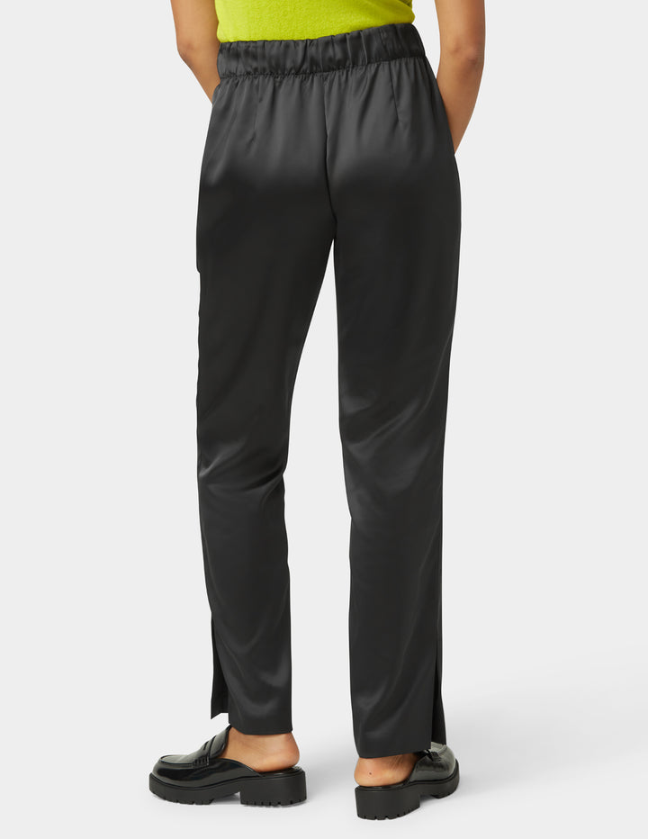 Black satin pants worn by a person on a white background
