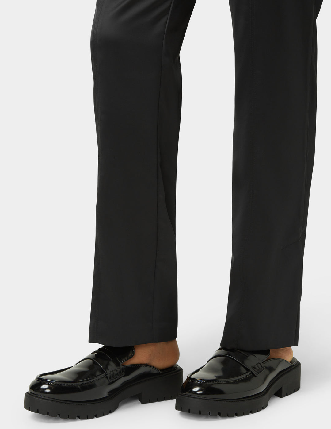 Black loafers worn with black pants on a white background