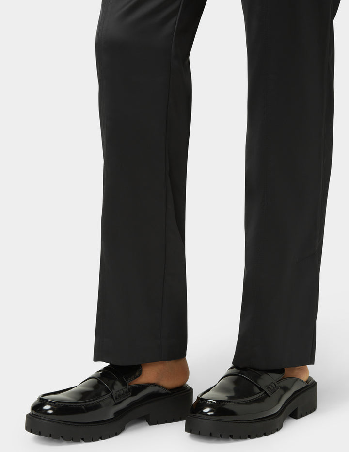 Black loafers worn with black pants on a white background